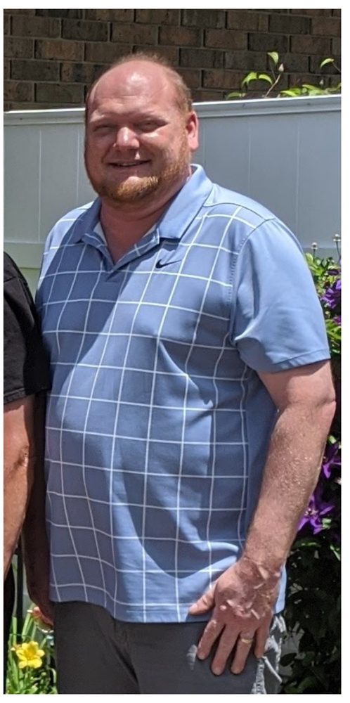 An earlier photograph of Stan outdoors in a light blue shirt.
