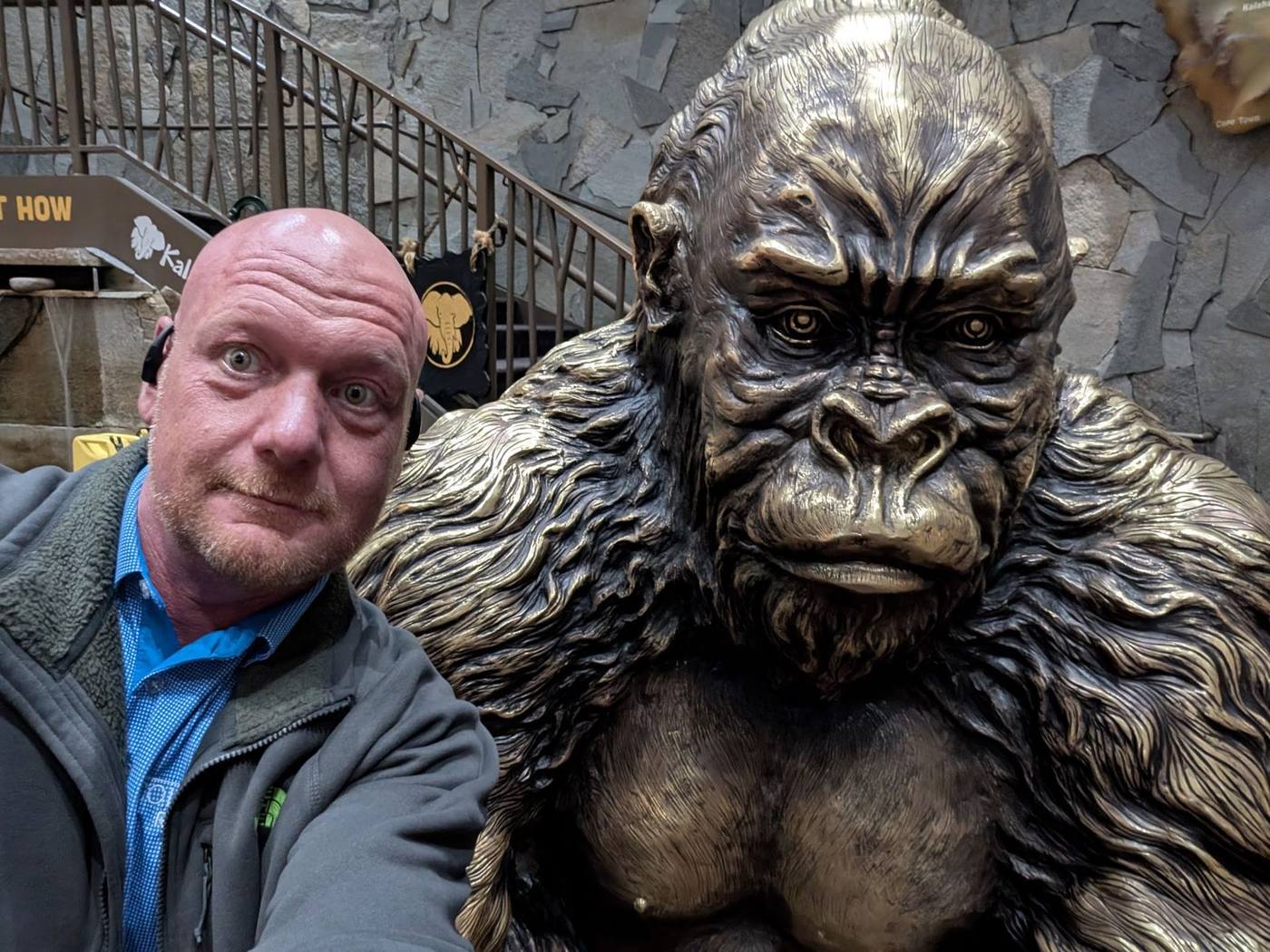 Stan taking a close-up photo next to a large bronze gorilla statue.